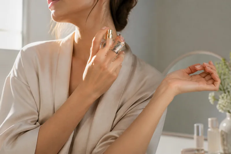 Mujer adulta aplicando perfume correctamente en el lateral del cuello y los puntos de pulso